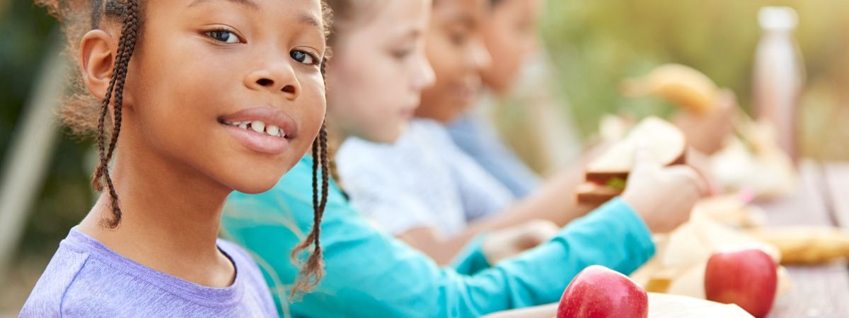 Children eating a healthy picnic lunch at an outdoor table